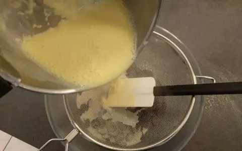 Verser la crème anglaise à travers une passoire fine pour obtenir une texture lisse.