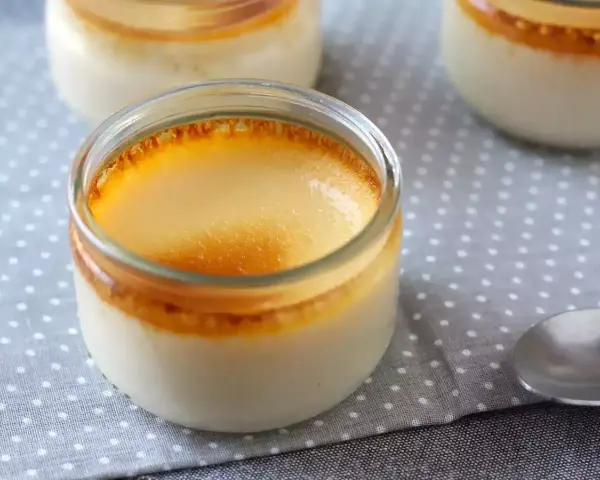 Trois pots de crème aux œufs, avec une croûte caramélisée dorée, sur une nappe à pois.
