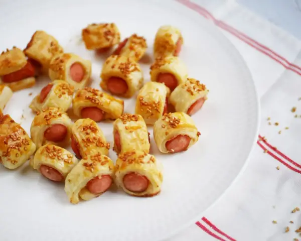 Une assiette de feuilleté saucisse dorés, parsemés de graines de sésame. Parfait pour un apéritif gourmand.