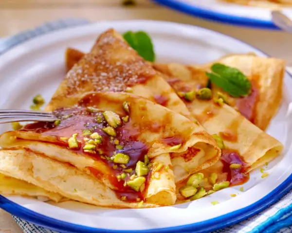 Délicieuses crêpes salées au beurre, garnies de pistaches concassées et d'un coulis rouge. Une touche de menthe apporte de la fraîcheur.