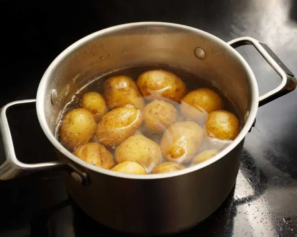 Pommes de terre entières dans une casserole d'eau bouillante, prêtes pour le temps de cuisson à l'eau.