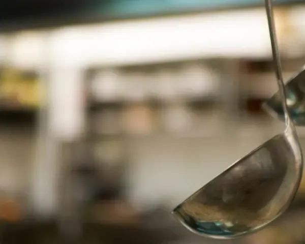 Deux louches en métal suspendues dans une cuisine. L'une est au premier plan, l'autre est floue en arrière-plan.