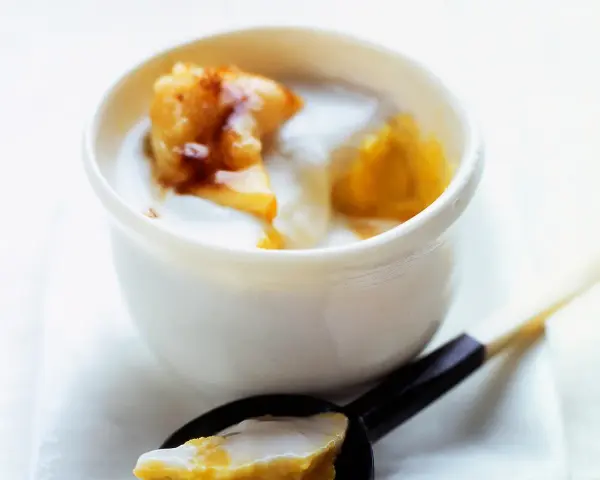 Délicieux dessert lait de coco crémeux avec des morceaux de fruits caramélisés. Une cuillère en est prête à être dégustée.