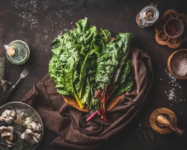 Blettes fraîches, ail, herbes et épices pour une délicieuse recette blette. Huile d'olive et sel complètent les ingrédients.