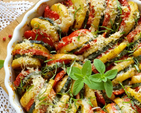 Un délicieux tian de légumes, aux rondelles de pommes de terre, courgettes et tomates, gratiné au fromage et parsemé d'herbes fraîches.