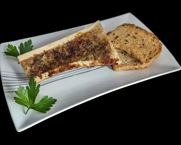 Un os à moelle rôti, assaisonné et garni de persil, servi avec des toasts grillés sur une assiette blanche.