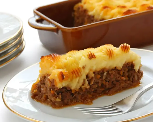 Une part de hachis parmentier, prêt pour la cuisson chaleur tournante, sur une assiette blanche.
