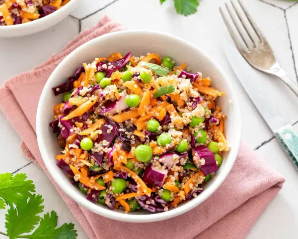 Salade quinoa colorée avec carottes râpées, chou rouge, petits pois et edamame. Un plat sain et savoureux.