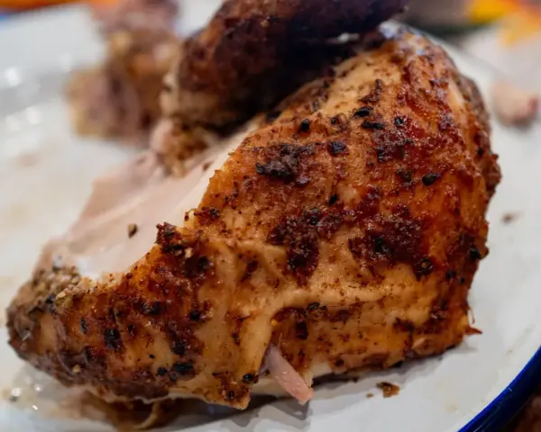 Un morceau de poulet braisé, doré et savoureux, est servi sur une assiette blanche.