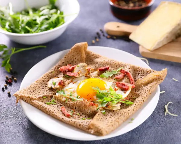Une galette de sarrasin garnie d'un œuf au plat, de lardons et de champignons. Un délice pour un petit-déjeuner ou un brunch.