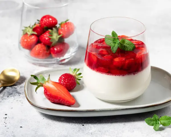 Délicieux panna cotta fraise, garni de fruits rouges frais et d'une touche de menthe. Un dessert léger et fruité.