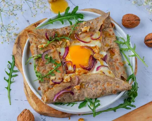 Délicieuse galette de sarrasin garnie d'un œuf, oignons rouges et noix. Parfait pour un repas pour 4 personnes.