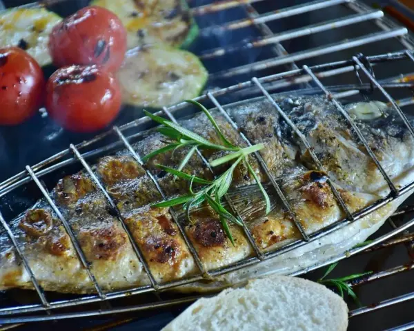 Dorade au barbecue, grillée à la perfection avec des tomates et des courgettes. Une branche de romarin parfume ce plat savoureux.
