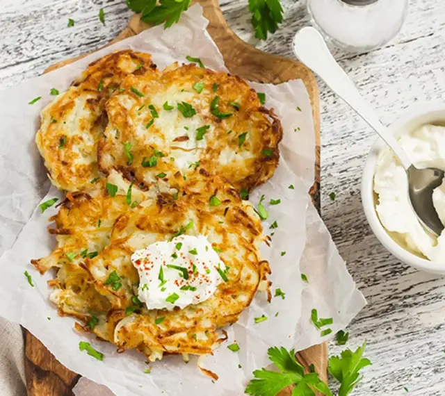 Délicieux rapé de pomme de terre doré, garni de crème fraîche et de persil, prêt à être dégusté avec une touche de paprika.