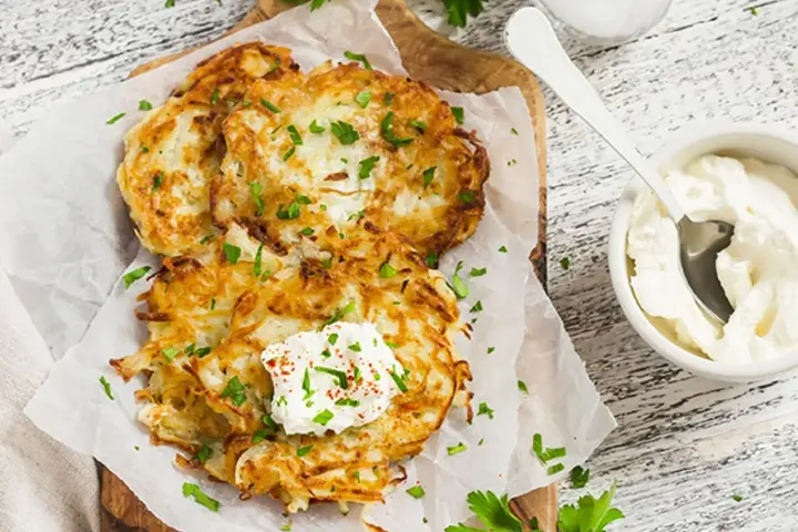 Délicieux rapé de pomme de terre doré, garni de crème fraîche et de persil, prêt à être dégusté avec une touche de paprika.