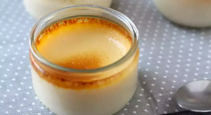 Trois pots de crème aux œufs, avec une croûte caramélisée dorée, sur une nappe à pois.