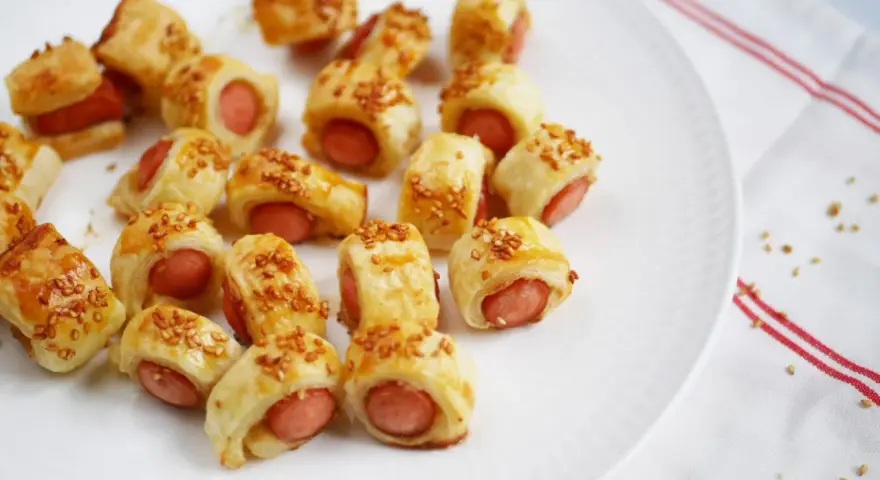 Une assiette de feuilleté saucisse dorés, parsemés de graines de sésame. Parfait pour un apéritif gourmand.
