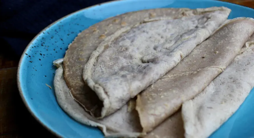 Galettes de sarrasin, naturellement sans gluten, sur une assiette bleue. La farine de blé noir donne cette texture rustique.