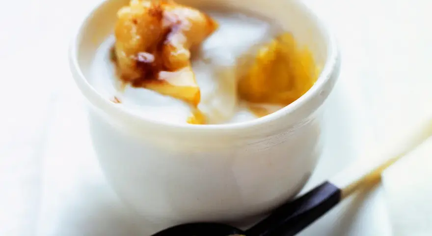 Délicieux dessert lait de coco crémeux avec des morceaux de fruits caramélisés. Une cuillère en est prête à être dégustée.