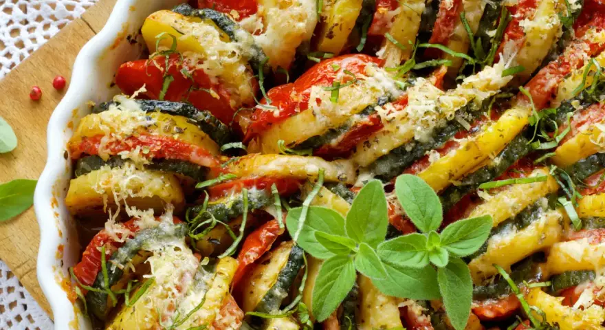 Un délicieux tian de légumes, aux rondelles de pommes de terre, courgettes et tomates, gratiné au fromage et parsemé d'herbes fraîches.