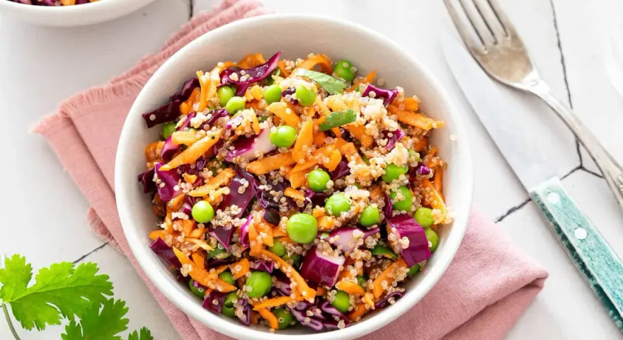 Salade quinoa colorée avec carottes râpées, chou rouge, petits pois et edamame. Un plat sain et savoureux.