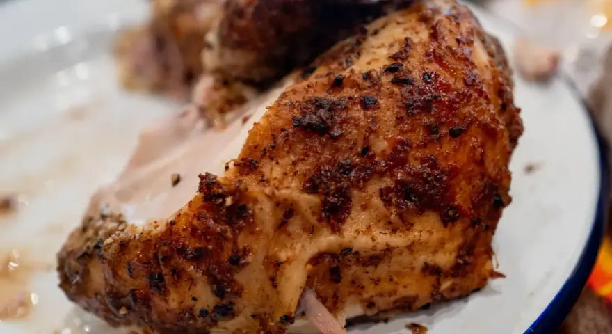 Un morceau de poulet braisé, doré et savoureux, est servi sur une assiette blanche.