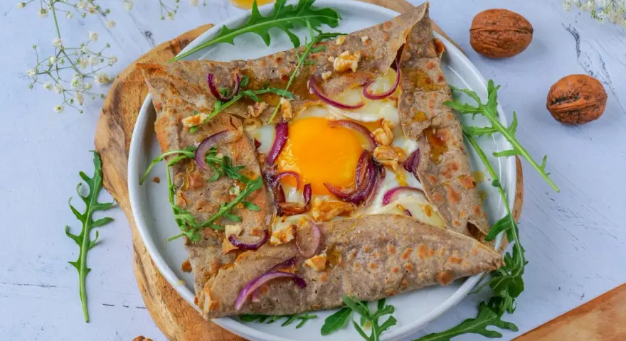 Délicieuse galette de sarrasin garnie d'un œuf, oignons rouges et noix. Parfait pour un repas pour 4 personnes.