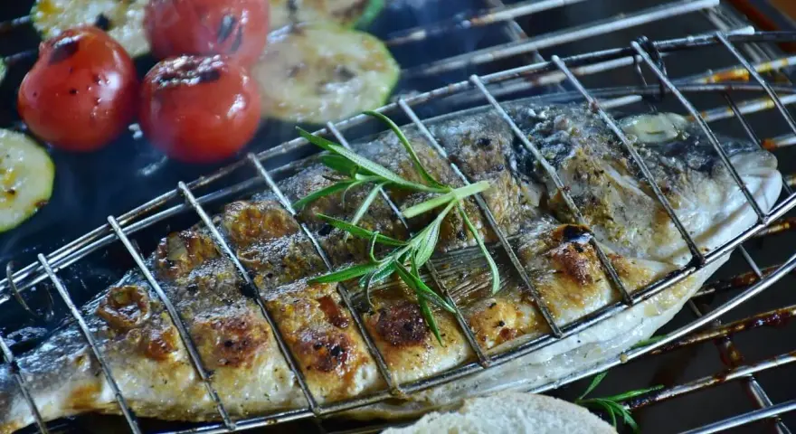 Dorade au barbecue, grillée à la perfection avec des tomates et des courgettes. Une branche de romarin parfume ce plat savoureux.
