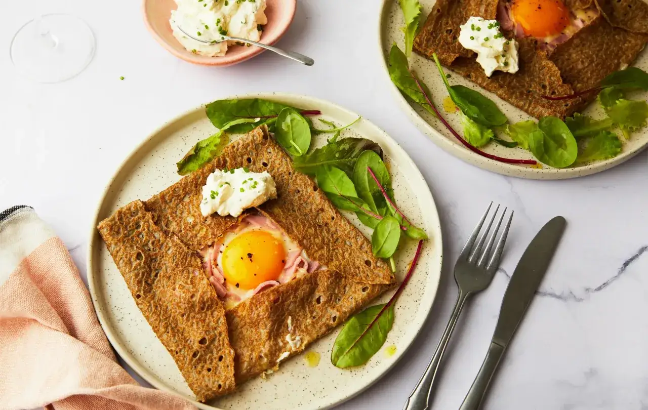 Une galette de sarrasin garnie d'un œuf au plat, de jambon et de fromage frais, accompagnée de salade. Un délice de crepe oeuf !