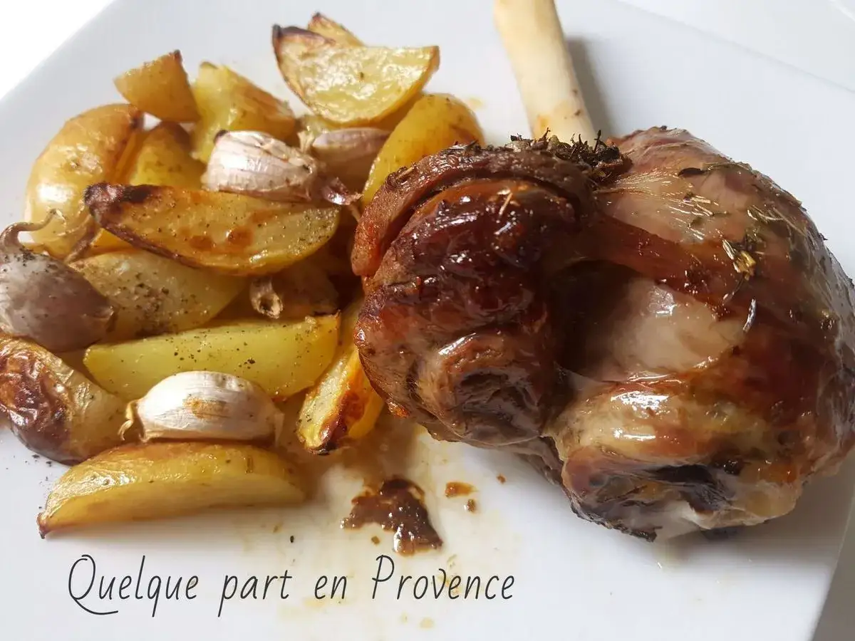 Une souris d'agneau rôtie, dorée et savoureuse, accompagnée de pommes de terre et d'ail au four.