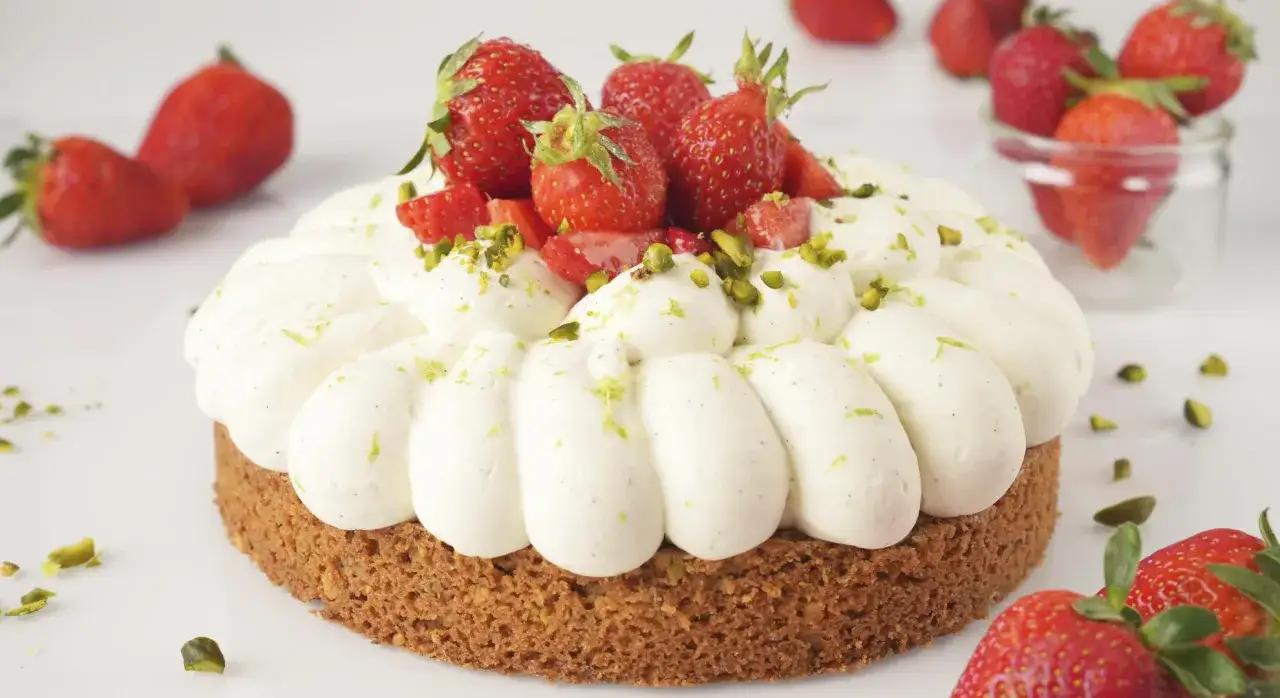 G&acirc;teau rond garni de fraises fra&icirc;ches et d'une onctueuse ganache chocolat blanc, parsem&eacute; de pistaches concass&eacute;es.