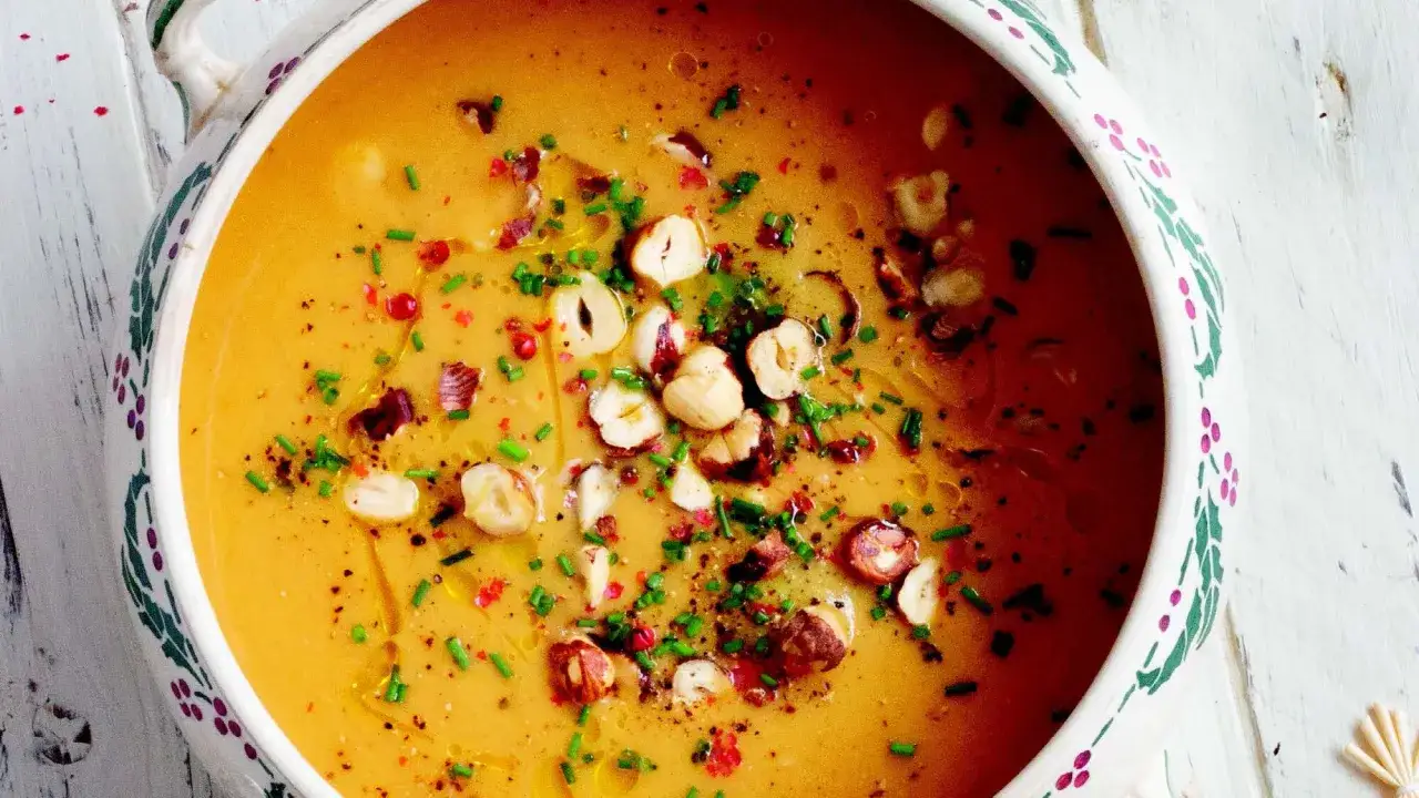 Soupe butternut onctueuse, garnie de noisettes concassées, de ciboulette ciselée et de baies roses. Un délice réconfortant.