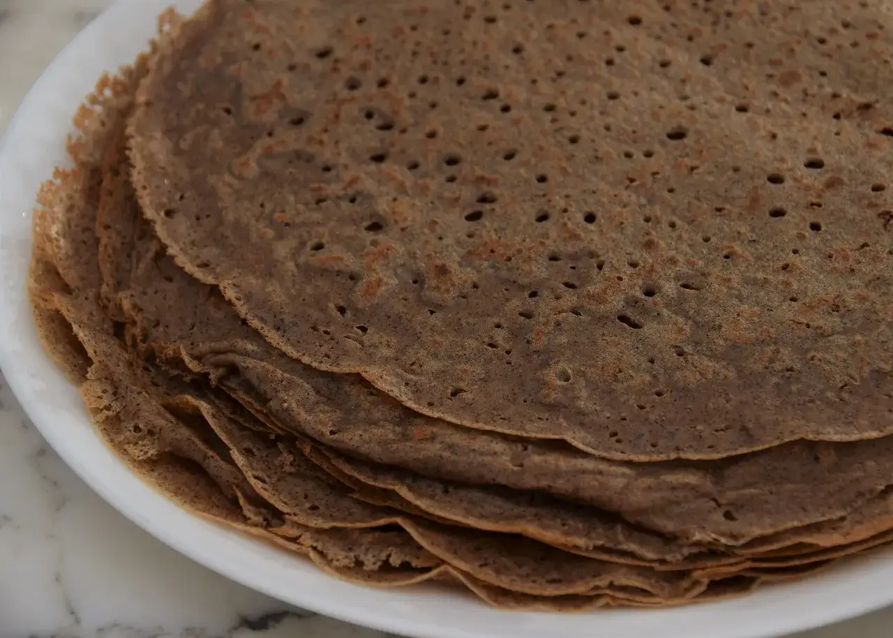 Pile de galettes de sarrasin sur une assiette blanche, parfaites pour une recette galette crepe.