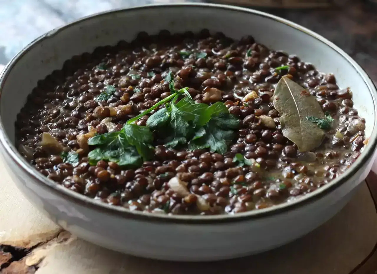 Bol de lentilles savoureux, garni de persil frais et d'une feuille de laurier. La quantit&eacute; de lentilles par personne est g&eacute;n&eacute;reuse.
