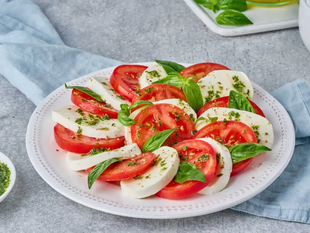 Une salade de tomates et mozzarella, garnie de basilic frais et d'herbes. Un d&eacute;lice estival simple et color&eacute;.