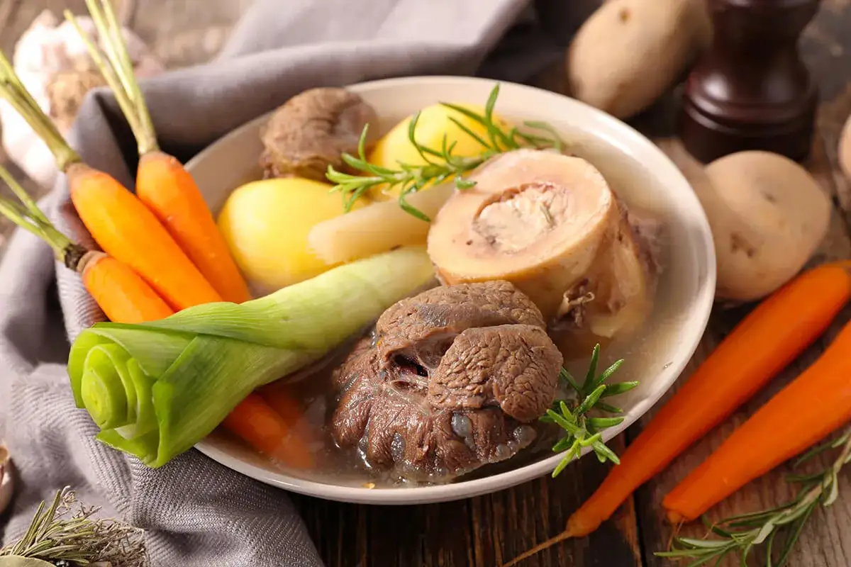 Un plat réconfortant de pot au feu, avec du bœuf, des carottes, des pommes de terre et des poireaux, garni de romarin.