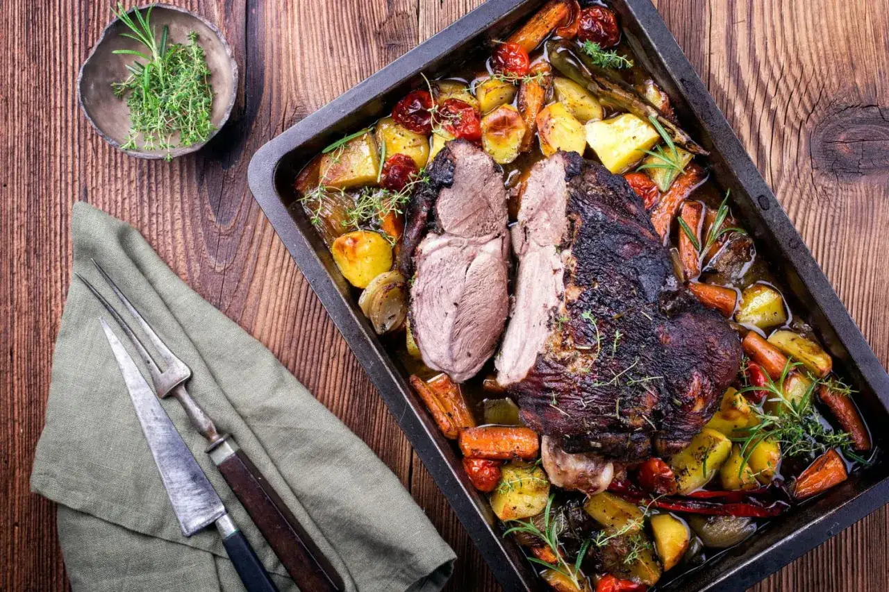 Gigot d'agneau au four cuisson lente, tendre et juteux, entour&eacute; de l&eacute;gumes r&ocirc;tis et d'herbes aromatiques.
