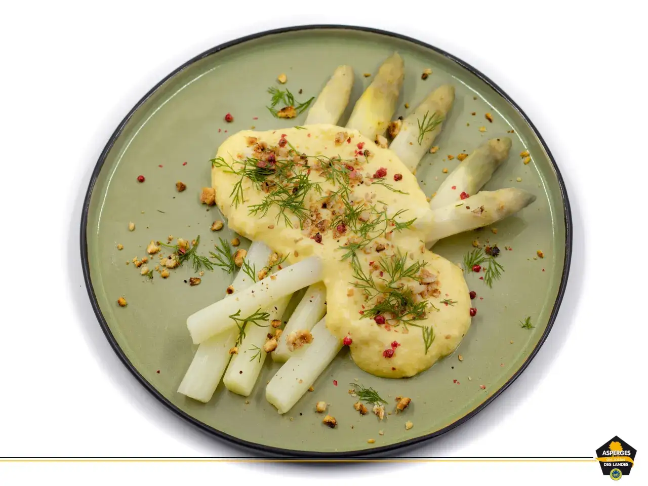 Asperges blanches servies avec une sauce mousseline onctueuse, garnies d'herbes fra&icirc;ches et de noix concass&eacute;es.