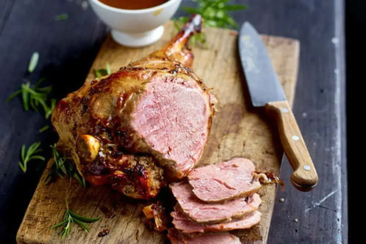 Gigot d'agneau rôti, tranché et servi avec une sauce savoureuse et des herbes fraîches. Un délice pour les papilles !