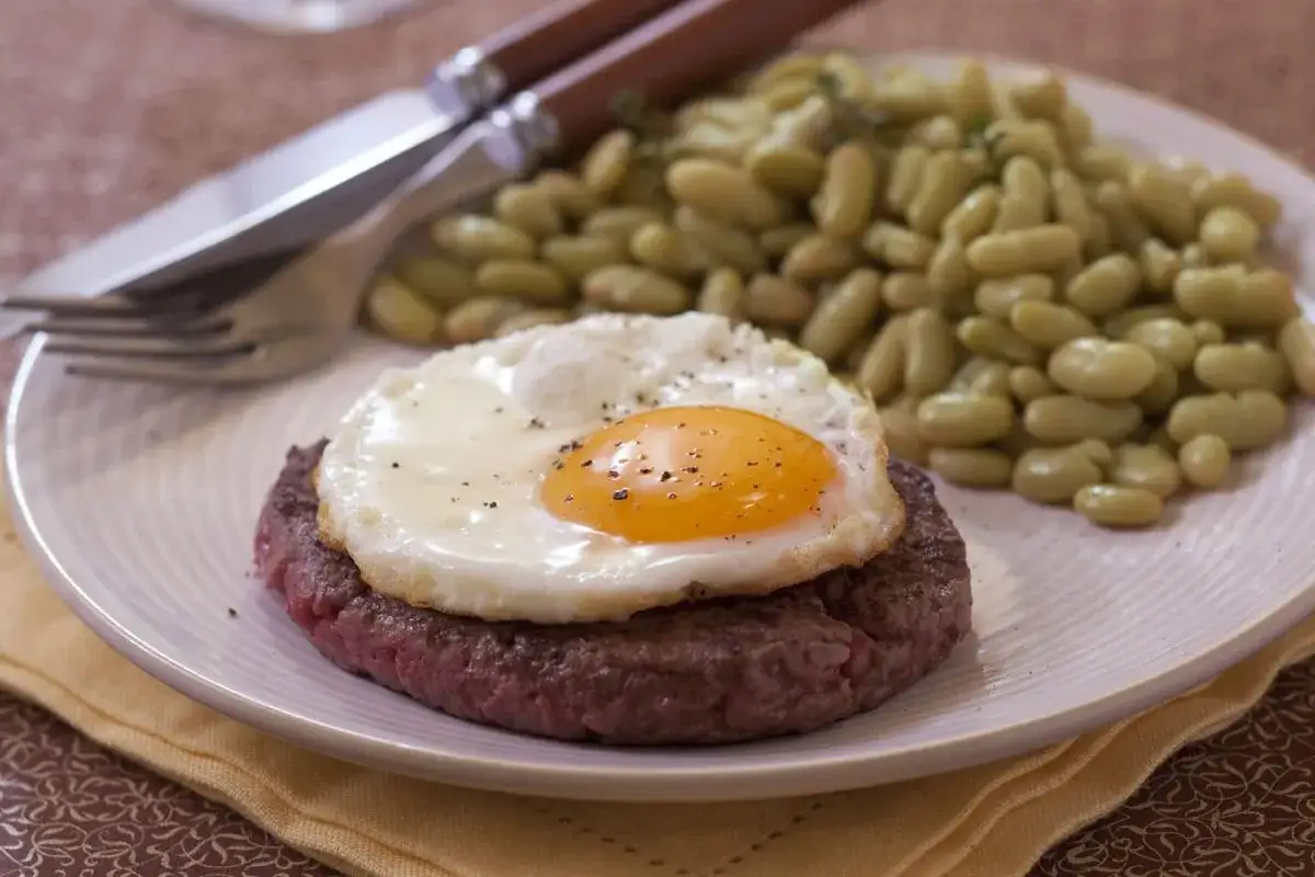 Un plat de steak a cheval avec un &oelig;uf au plat et des haricots verts. Un classique savoureux pr&ecirc;t &agrave; &ecirc;tre d&eacute;gust&eacute;.