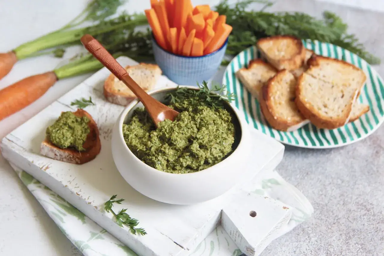 Un d&eacute;licieux pesto de fanes de carottes, servi avec des toasts grill&eacute;s et des b&acirc;tonnets de carottes.