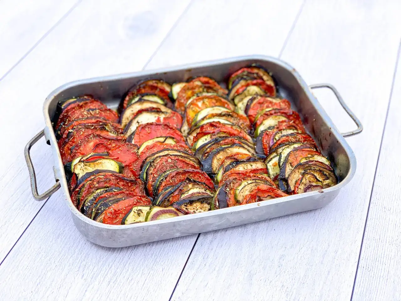Un plat de tian de l&eacute;gumes, joliment arrang&eacute; en rondelles altern&eacute;es de tomates, courgettes et aubergines, pr&ecirc;t &agrave; &ecirc;tre d&eacute;gust&eacute;.