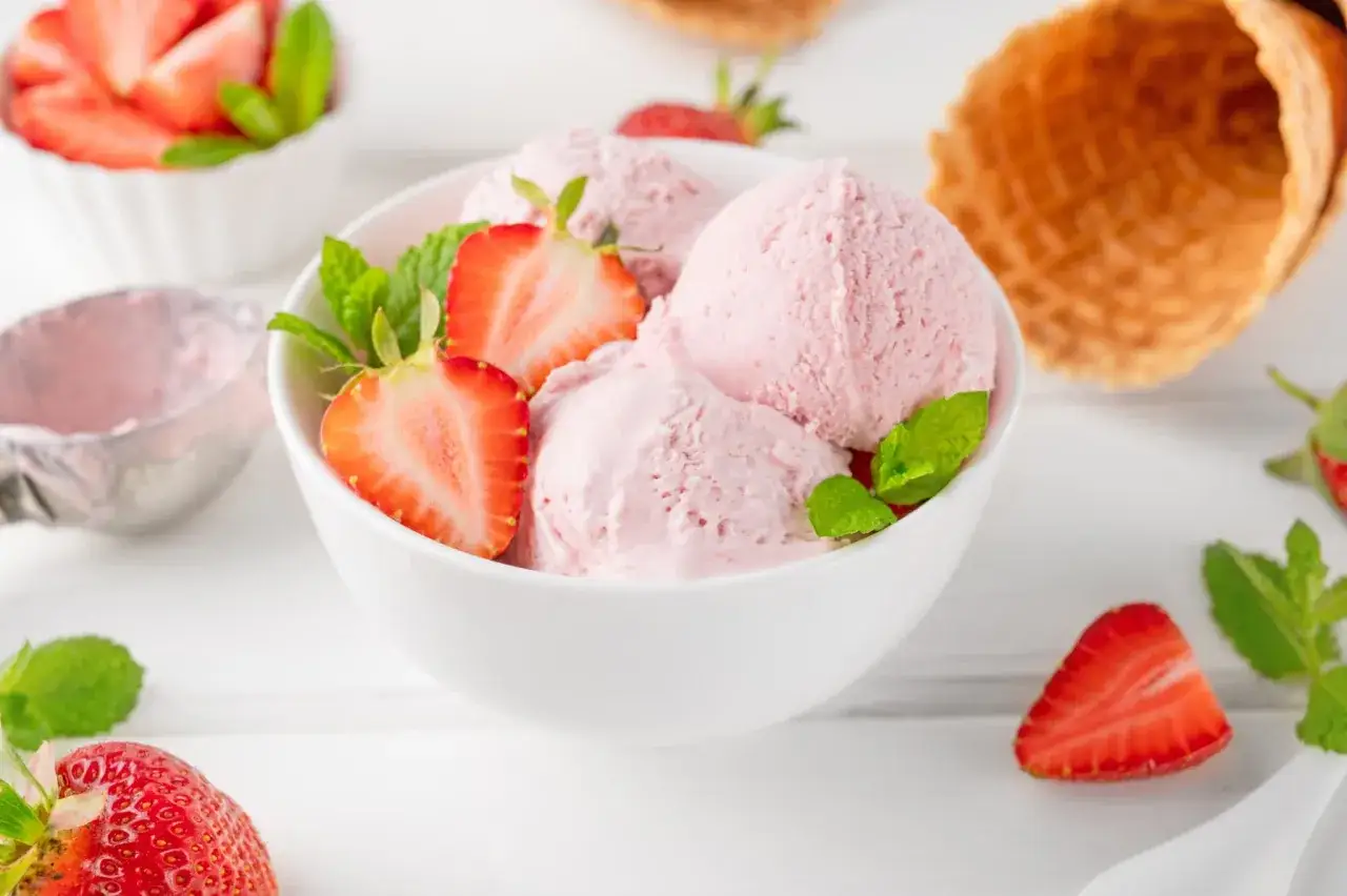 D&eacute;licieuse recette glace &agrave; la fraise sans sorbeti&egrave;re. Boules de glace rose p&acirc;le garnies de fraises fra&icirc;ches et de menthe.