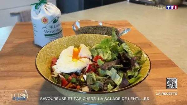 Une assiette colorée de salade de lentilles garnie d'un œuf poché, de légumes frais et de tomates. Un sac de lentilles vertes est visible en arrière-plan.