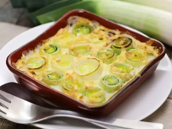 Un délicieux gratin de poireaux crémeux, prêt à être dégusté. Les poireaux coupés en rondelles sont nappés d'une sauce onctueuse et gratinés à la perfection.