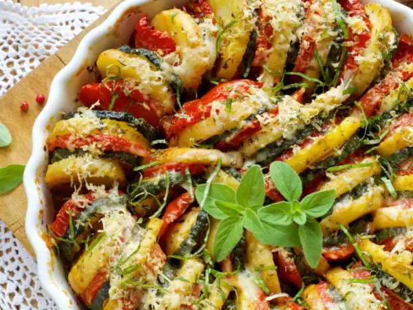 Un délicieux tian de légumes, aux rondelles de pommes de terre, courgettes et tomates, gratiné au fromage et parsemé d'herbes fraîches.