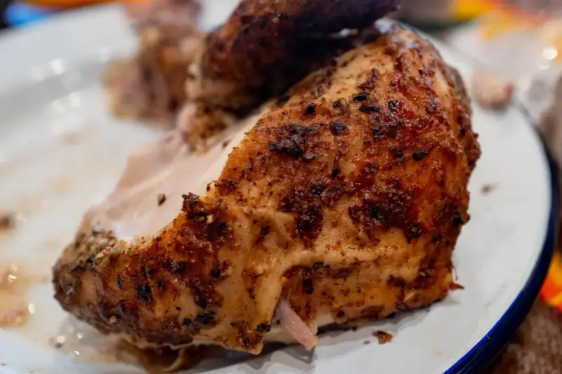 Un morceau de poulet braisé, doré et savoureux, est servi sur une assiette blanche.