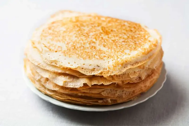 Pile de 10 crêpes sucrées dorées, prêtes à être garnies. Une recette simple pour un plaisir gourmand.